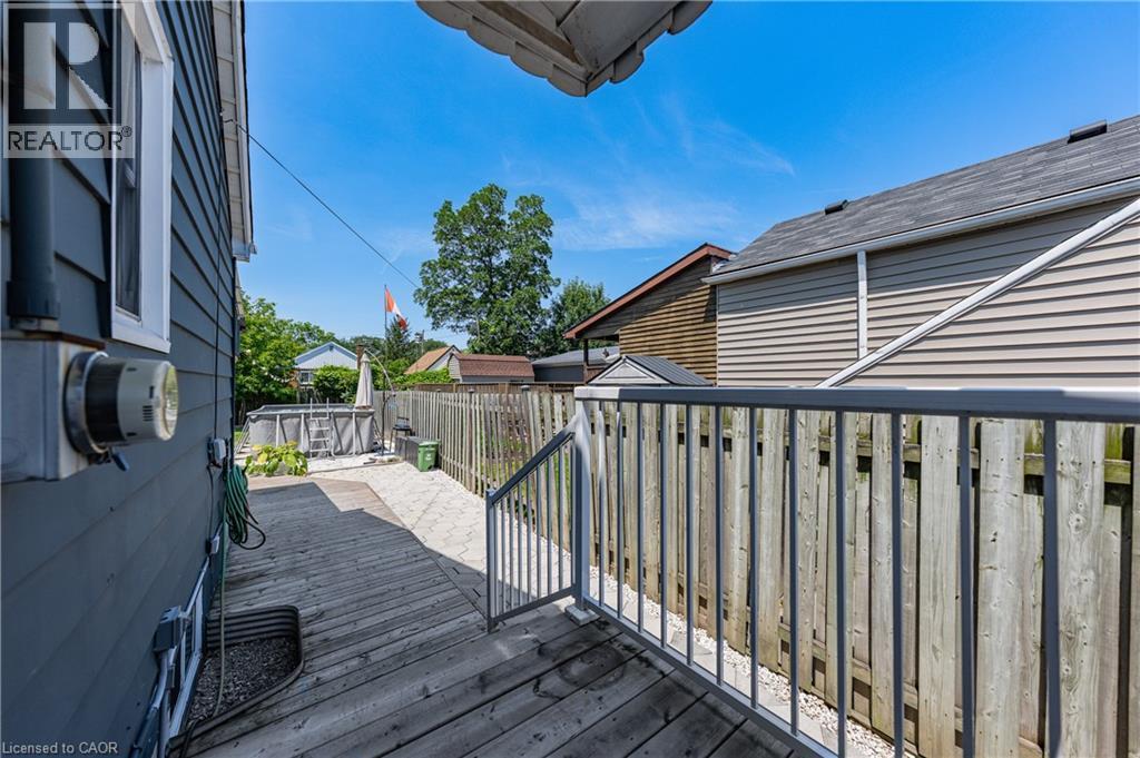 Expansive backyard featuring a wood-finish deck, privacy fencing, above-ground pool, and a gravel patio area - 621 Tate Avenue, Hamilton, ON - Outdoor With Deck Patio Veranda With Exterior