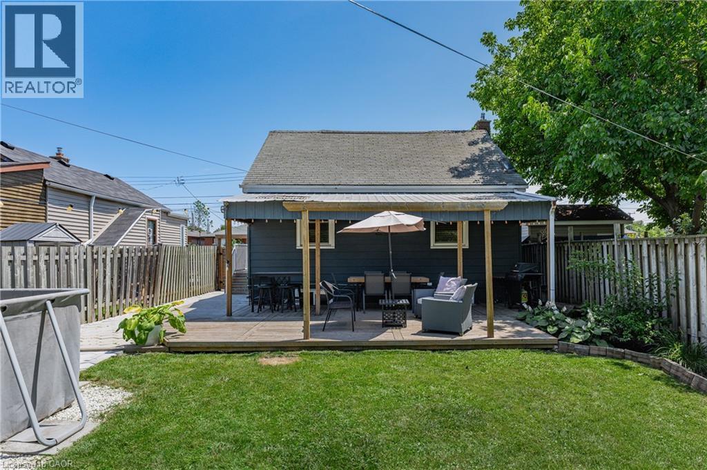 Expansive backyard featuring a manicured lawn, a wooden deck, and a covered patio area - 621 Tate Avenue, Hamilton, ON - Outdoor With Deck Patio Veranda