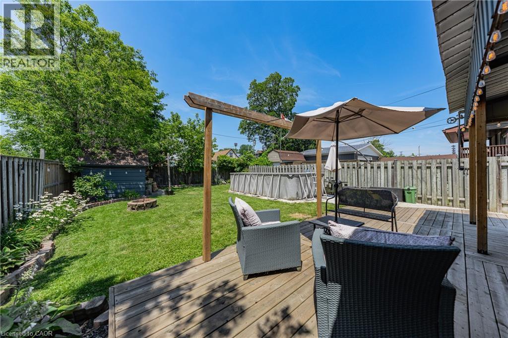 Expansive backyard featuring a wood deck, manicured lawn, and mature trees - 621 Tate Avenue, Hamilton, ON - Outdoor With Deck Patio Veranda