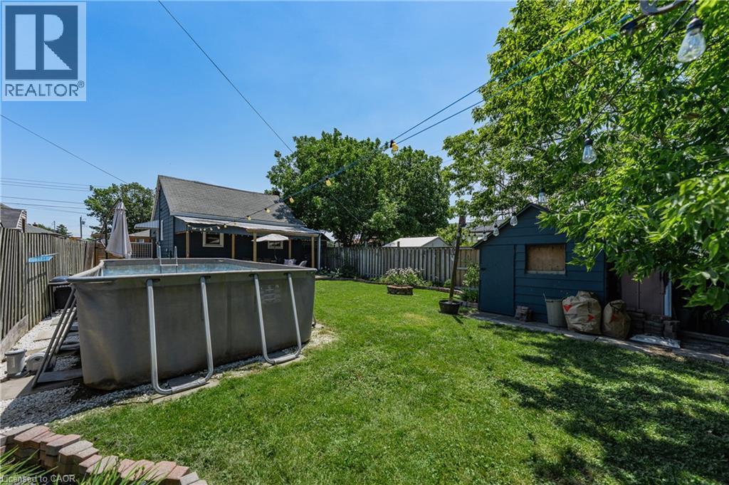 Expansive backyard featuring a lush lawn, a storage shed, and mature trees - 621 Tate Avenue, Hamilton, ON - Outdoor With Above Ground Pool