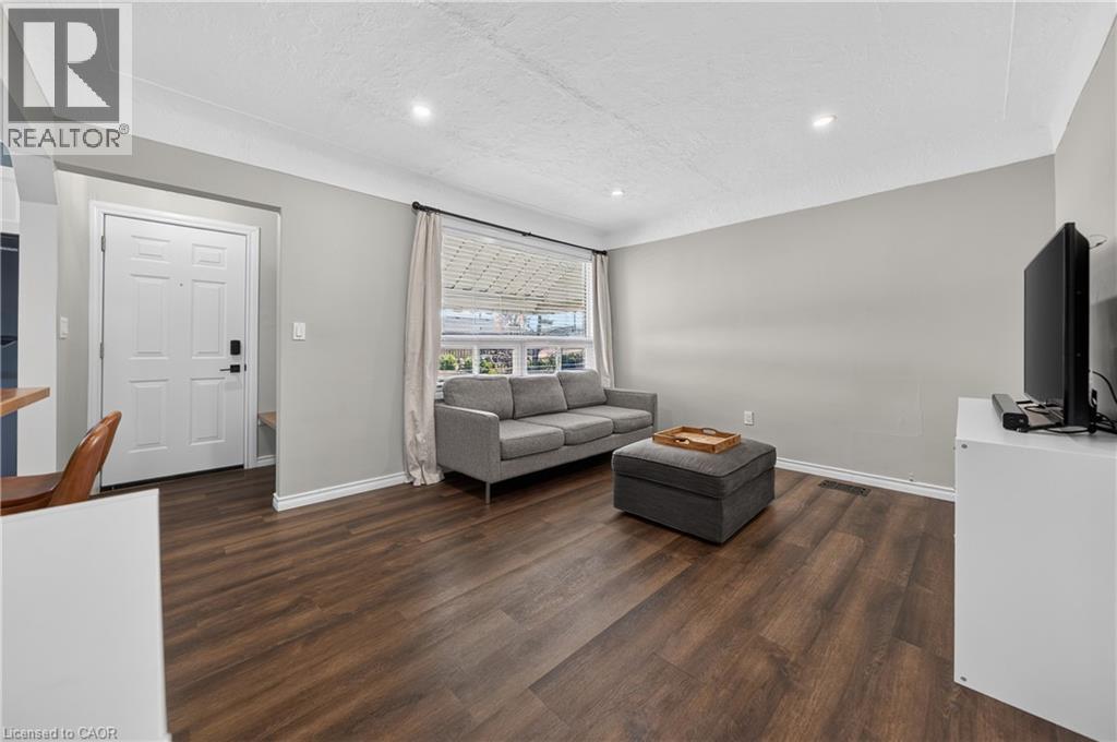 Spacious living area featuring wood-finish flooring, light gray wall paint, and recessed ceiling lighting - 621 Tate Avenue, Hamilton, ON - Indoor