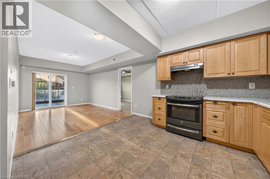 Kitchen with natural wood cabinetry, light-toned countertops, and a full range oven - 155 Water Street S Unit# 203, Cambridge, ON - Indoor Photo Showing Kitchen