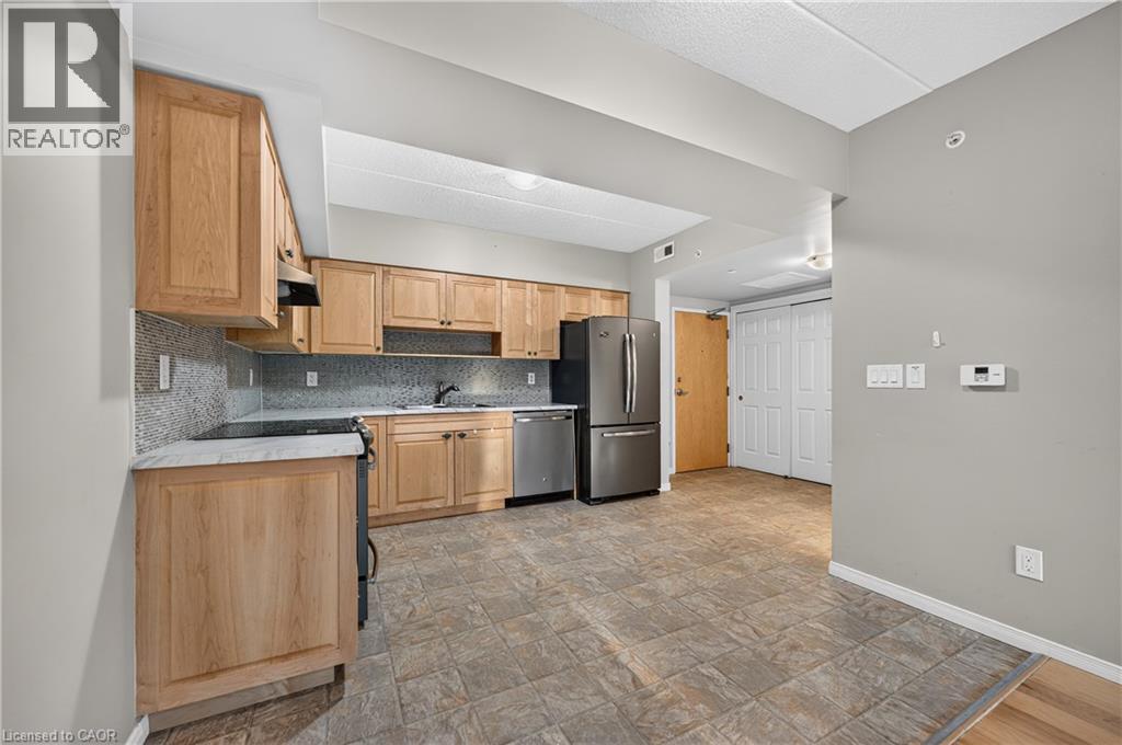 Kitchen featuring light wood cabinetry, stainless steel appliances, a tile backsplash, and light-toned countertops - 155 Water Street S Unit# 203, Cambridge, ON - Indoor Photo Showing Kitchen