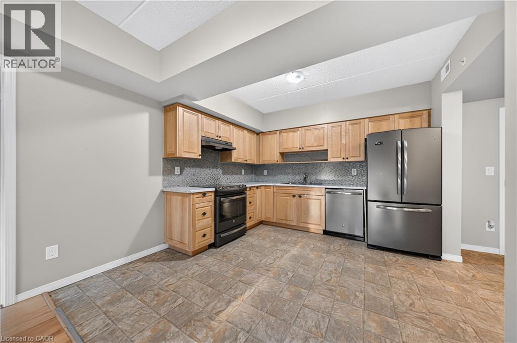 Kitchen featuring natural wood-finish cabinetry, tile flooring, and light-toned countertops - 155 Water Street S Unit# 203, Cambridge, ON - Indoor Photo Showing Kitchen With Stainless Steel Kitchen