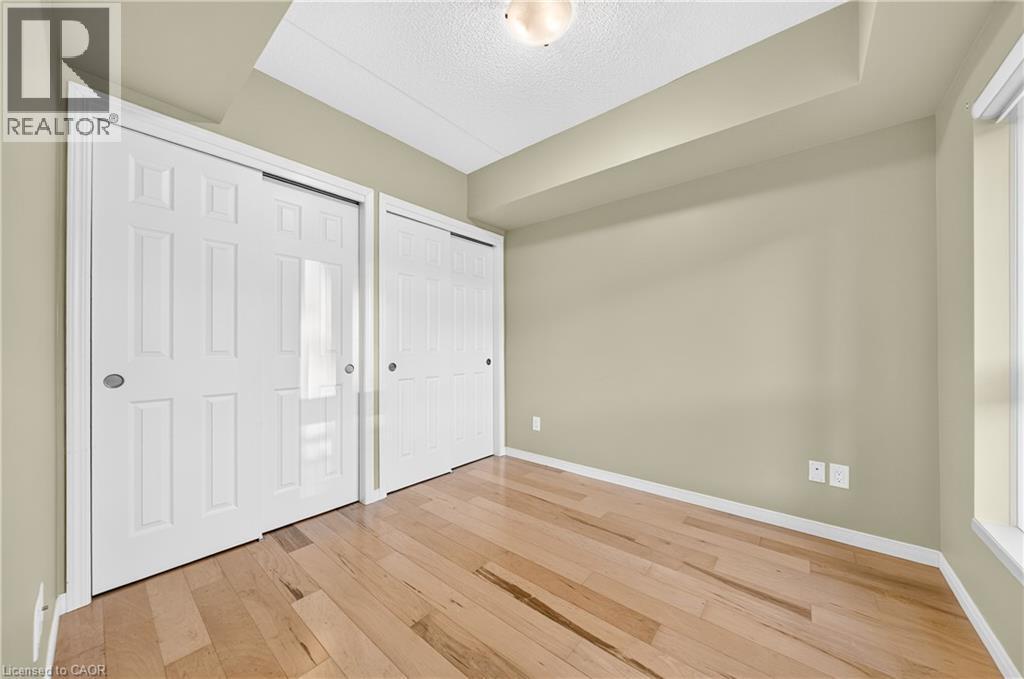Light wood-finish flooring complemented by neutral wall tones - 155 Water Street S Unit# 203, Cambridge, ON - Indoor Photo Showing Other Room