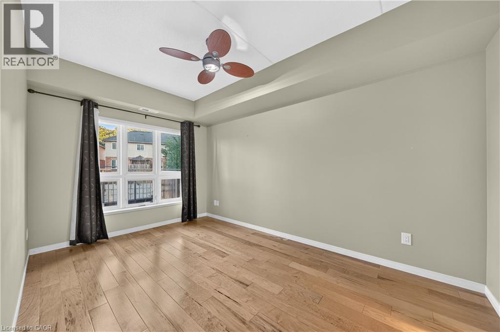 Room featuring wood-finish flooring, a multi-pane window, and a ceiling fan with integrated lighting - 155 Water Street S Unit# 203, Cambridge, ON - Indoor Photo Showing Other Room