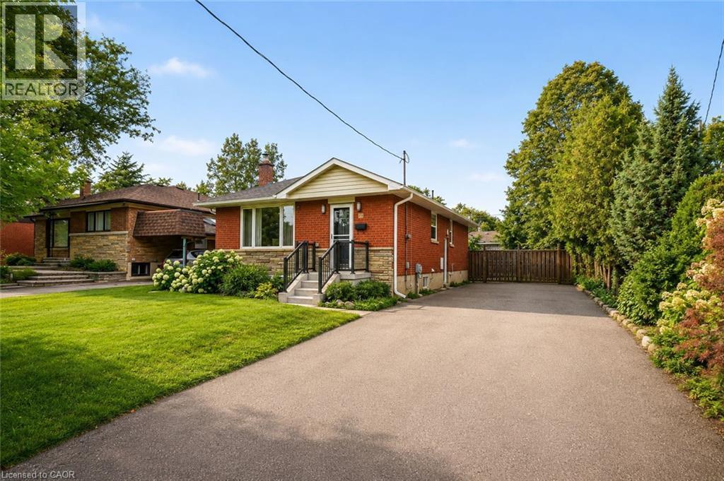 Brick and stone facade residence featuring a front lawn and paved driveway - 715 Drury Lane, Burlington, ON - Outdoor With Facade