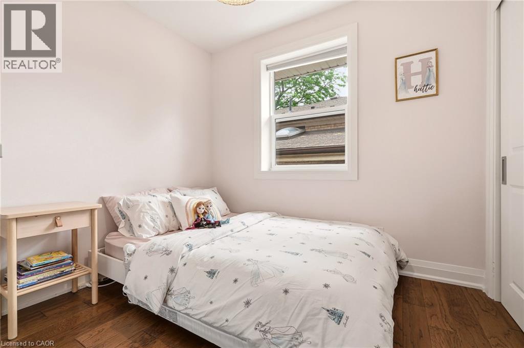 Light-filled room featuring wood-finish flooring, white baseboards, and a single window with white trim - 715 Drury Lane, Burlington, ON - Indoor Photo Showing Bedroom