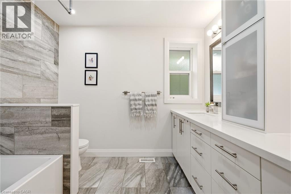 Modern bathroom featuring large format gray-toned tile flooring and a matching tiled shower surround - 715 Drury Lane, Burlington, ON - Indoor Photo Showing Bathroom