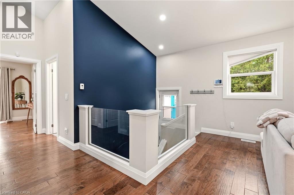 Open concept upper level featuring wood-finish flooring and a glass panel railing system - 715 Drury Lane, Burlington, ON - Indoor Photo Showing Other Room
