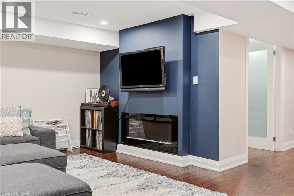 Media wall featuring a built-in electric fireplace, recessed lighting, and rich wood-finish flooring - 715 Drury Lane, Burlington, ON - Indoor
