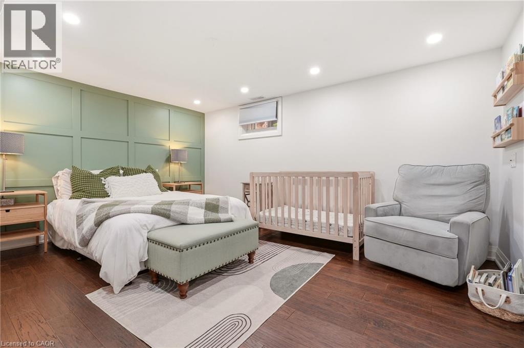Spacious room featuring rich wood-finish flooring, recessed lighting, and a decorative paneled accent wall - 715 Drury Lane, Burlington, ON - Indoor Photo Showing Bedroom