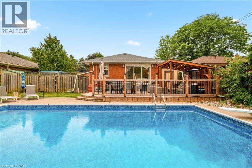 Fenced backyard featuring an in-ground swimming pool, concrete pool deck, and a multi-level wood deck - 715 Drury Lane, Burlington, ON - Outdoor With In Ground Pool With Deck Patio Veranda With Backyard