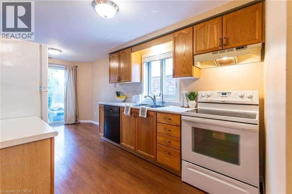 Kitchen featuring wood-finish flooring, natural wood cabinetry, a white countertop, and a double-basin sink - 426 Downsview Place, Waterloo, ON - Indoor Photo Showing Kitchen With Double Sink