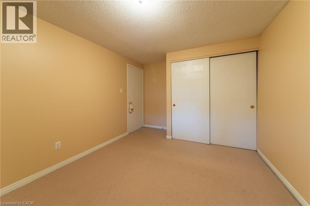 Room featuring tan walls, light brown carpeting, white baseboards, and a textured ceiling - 426 Downsview Place, Waterloo, ON - Indoor Photo Showing Other Room