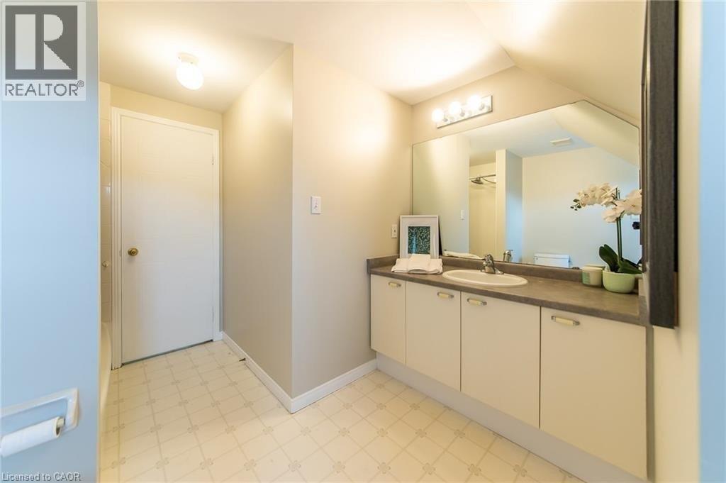 Bathroom vanity featuring an integrated sink, broad wall-mounted mirror, and overhead four-bulb light fixture - 426 Downsview Place, Waterloo, ON - Indoor Photo Showing Other Room