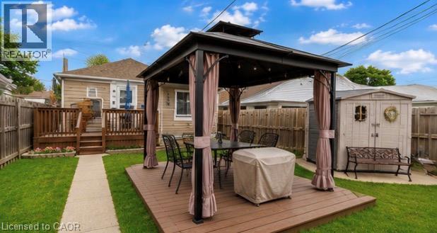 Expansive backyard featuring a gazebo on a wood-finish deck, a concrete patio, a storage shed, a manicured lawn, and wood privacy fencing - 237 Paling Avenue, Hamilton, ON - Outdoor With Deck Patio Veranda With Exterior