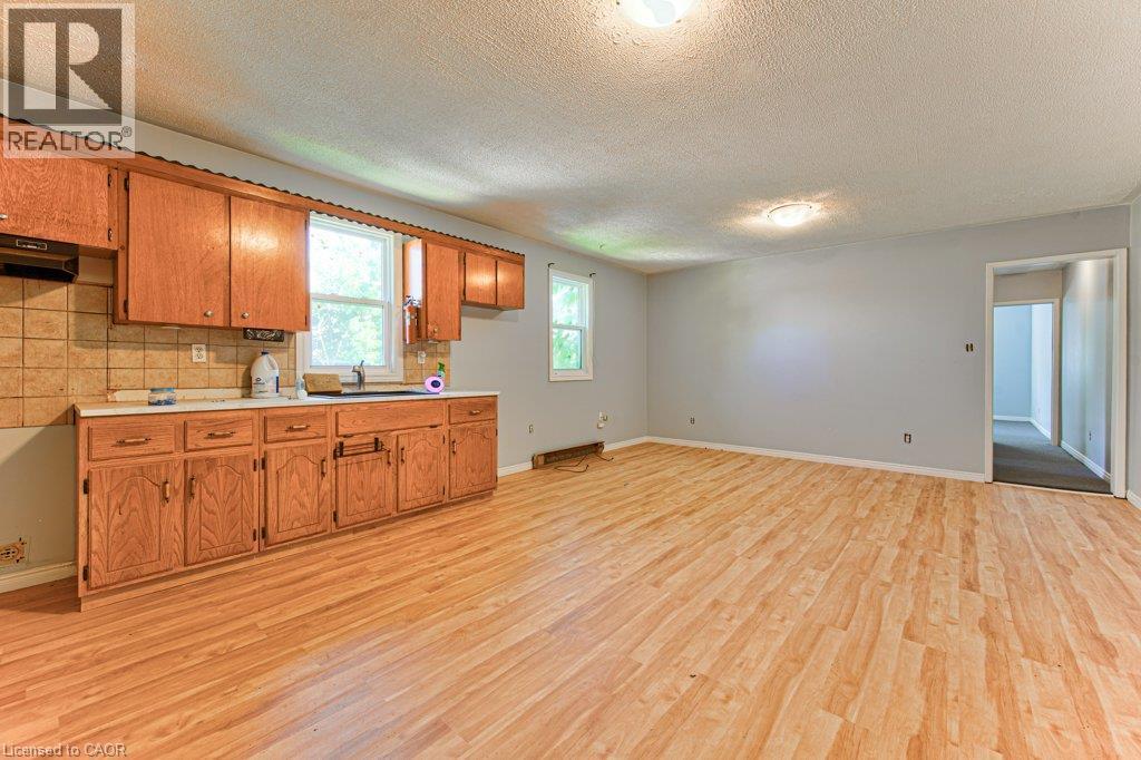 Kitchen and living area featuring wood-finish flooring, oak cabinetry, and light gray walls - 819 Duke Street, Cambridge, ON - Indoor Photo Showing Kitchen