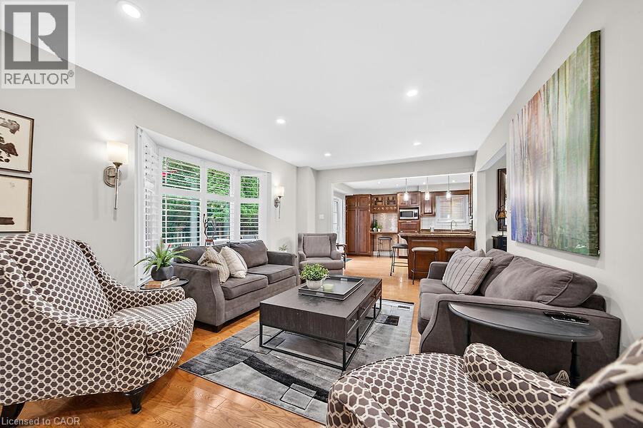 Spacious living area featuring wood-finish flooring, recessed lighting, and a bay window with plantation shutters - 30 Carriagegate Drive, Hamilton, ON - Indoor Photo Showing Living Room