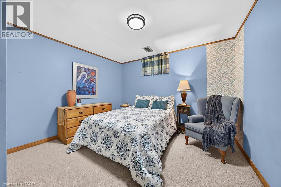 Carpeted room featuring light blue walls with wood trim and a patterned accent wall - 30 Carriagegate Drive, Hamilton, ON - Indoor Photo Showing Bedroom