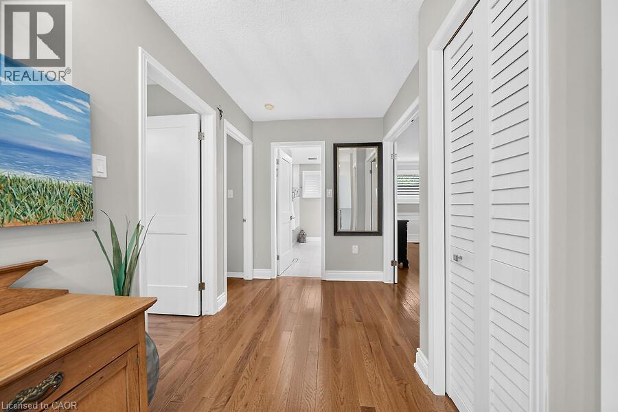 Hallway featuring wood-finish flooring, light gray walls, white trim, and bi-fold louvered doors - 30 Carriagegate Drive, Hamilton, ON - Indoor Photo Showing Other Room