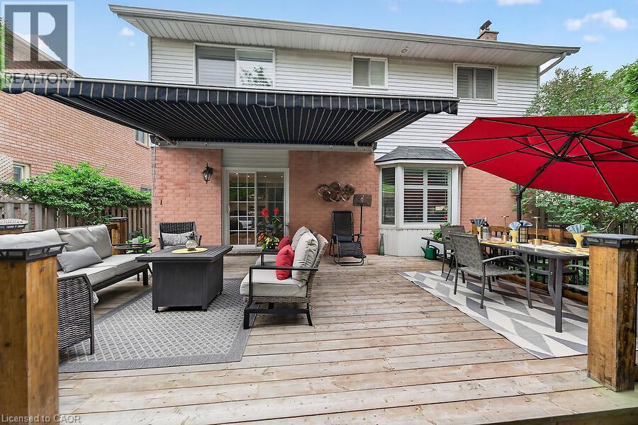 Expansive outdoor wood-finish deck with an attached retractable awning, brick exterior, and a bay window - 30 Carriagegate Drive, Hamilton, ON - Outdoor With Deck Patio Veranda With Exterior