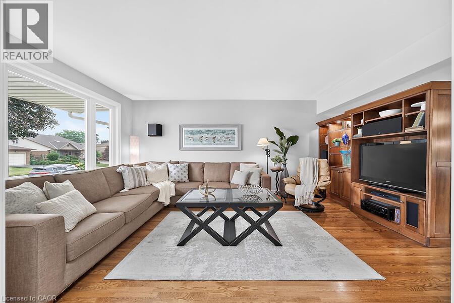Spacious living area featuring wood-finish flooring and ample natural light from large windows - 30 Carriagegate Drive, Hamilton, ON - Indoor Photo Showing Living Room