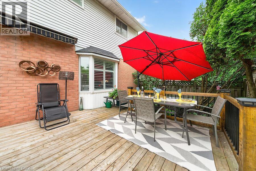 Wood-finish deck featuring a bay window, brick and siding exterior, privacy fencing, and mature perimeter trees - 30 Carriagegate Drive, Hamilton, ON - Outdoor With Deck Patio Veranda With Exterior