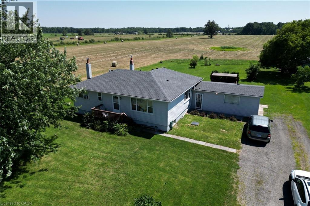 Ranch-style residence featuring a gray shingle roof, light blue siding, and two prominent brick chimneys - 958 Highland Road E, Hamilton, ON