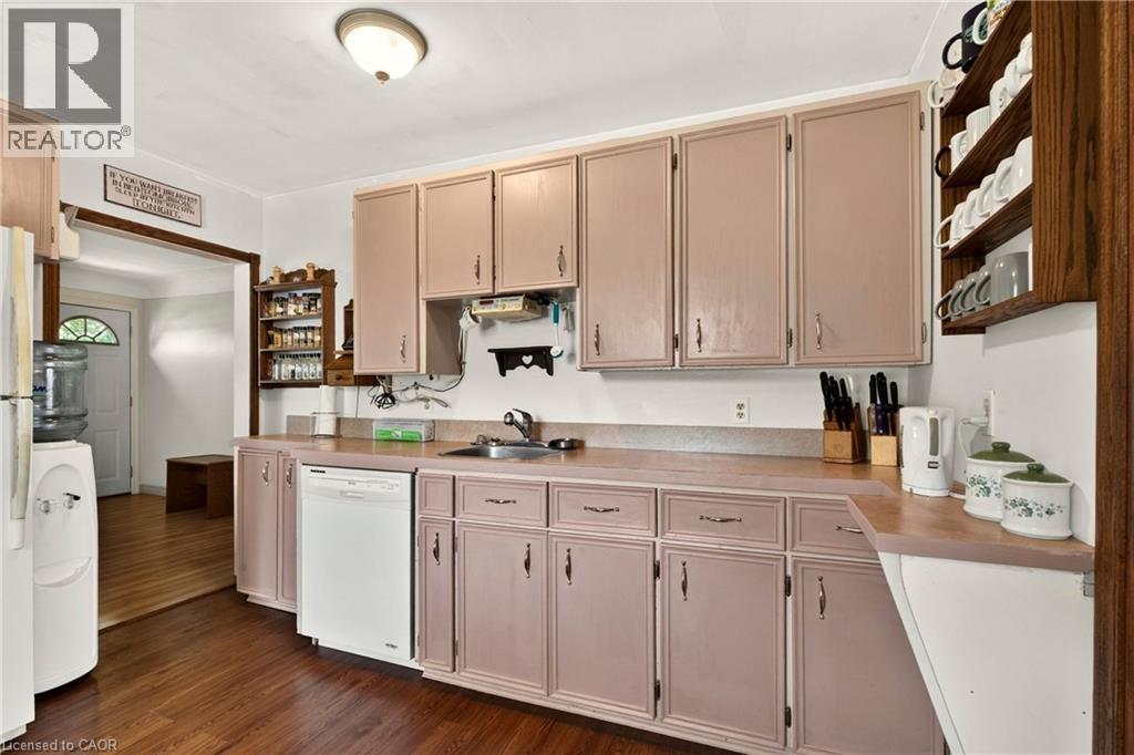 Kitchen featuring wood-finish flooring, ample cabinetry, integrated sink, and white appliances - 958 Highland Road E, Hamilton, ON