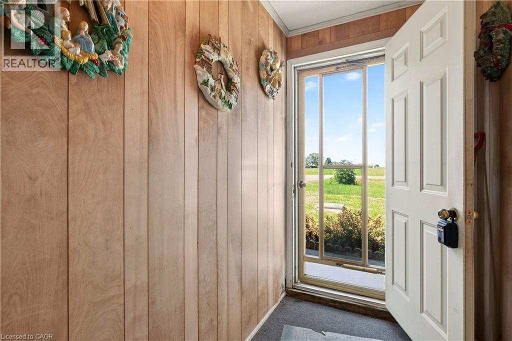 Entryway featuring panel wall finishes, carpet flooring, a white paneled door, and an exterior screen door - 958 Highland Road E, Hamilton, ON