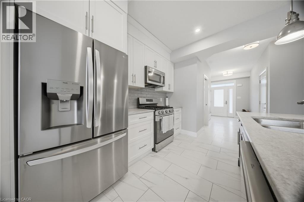 Contemporary kitchen featuring stainless steel appliances, white cabinetry, light countertops, and large format floor tiling - 107 Stephenson Way, Palmerston, ON - Indoor Photo Showing Kitchen With Stainless Steel Kitchen With Upgraded Kitchen