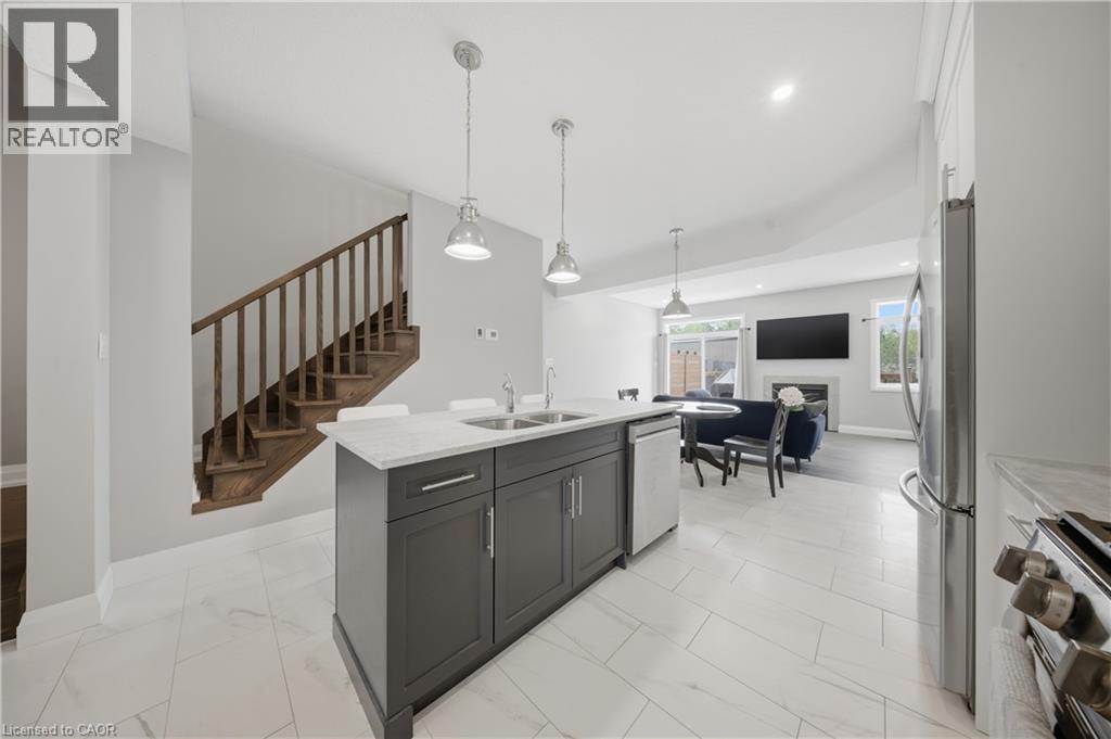 Open-concept main level featuring a kitchen island with dual sinks, pendant lighting, and stainless steel appliances - 107 Stephenson Way, Palmerston, ON - Indoor Photo Showing Kitchen With Double Sink