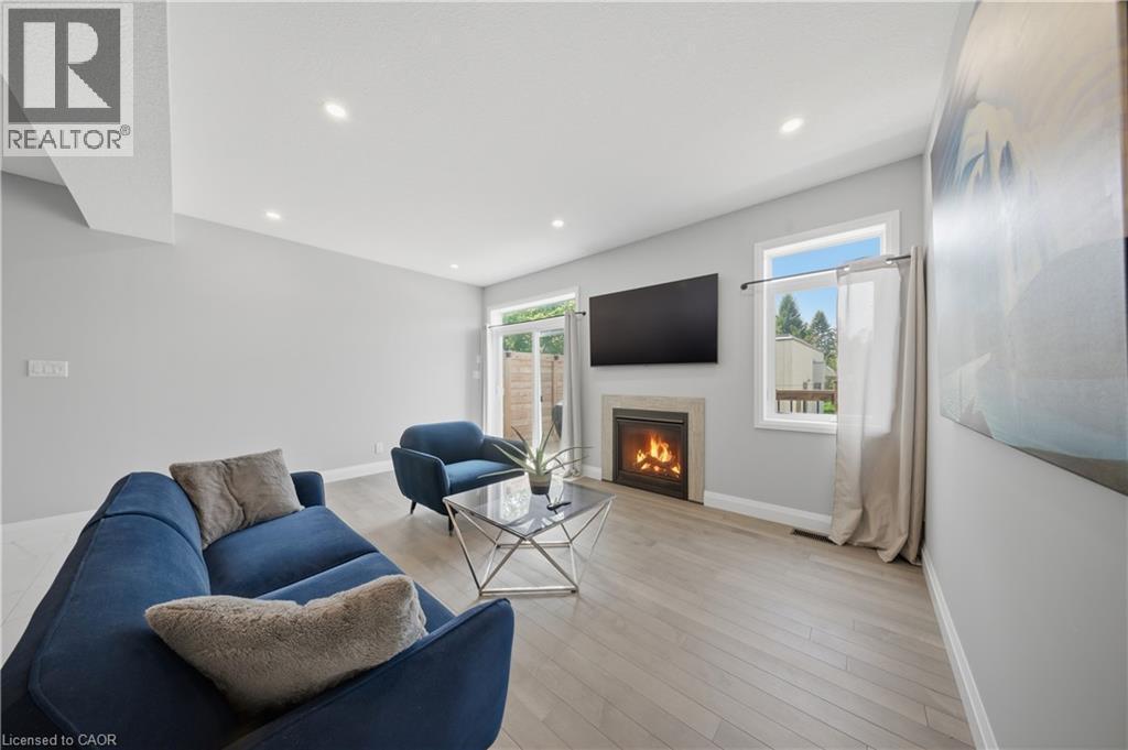 Living area featuring a stone surround fireplace with a built-in mantel, recessed lighting, and wood-finish flooring - 107 Stephenson Way, Palmerston, ON - Indoor Photo Showing Living Room With Fireplace