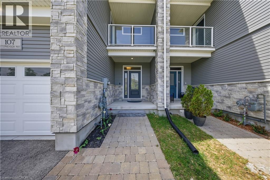 Stone and siding exterior with a garage door and paved walkway - 107 Stephenson Way, Palmerston, ON - Outdoor With Balcony