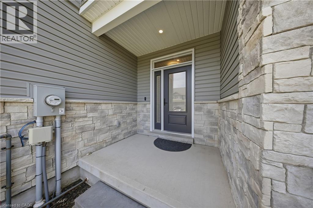 Inviting front entry featuring a concrete porch, dark gray entry door with partial glass, integrated sidelight, and an overhead porch light - 107 Stephenson Way, Palmerston, ON - Outdoor With Exterior