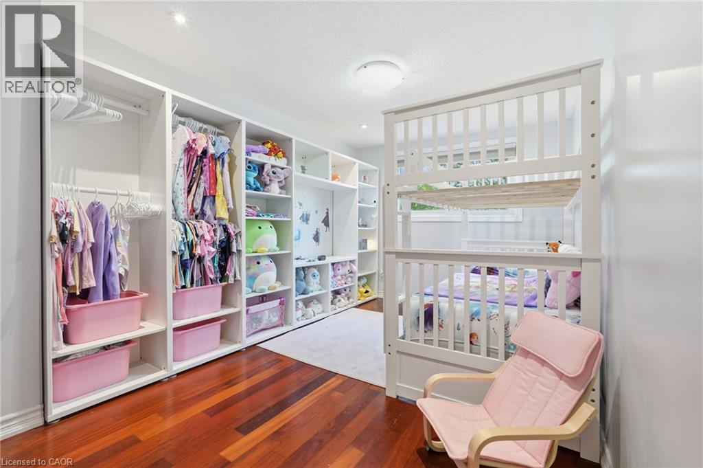 Custom built-in white cabinetry with integrated shelving and hanging rods, complemented by wood-finish flooring and a flush-mount ceiling light fixture - 86 San Remo Drive, Hamilton, ON - Indoor With Storage