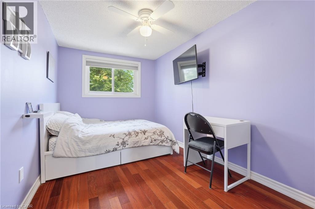 Bright room featuring rich wood-finish flooring, a single window with white trim, and a ceiling fan - 86 San Remo Drive, Hamilton, ON - Indoor Photo Showing Bedroom
