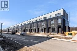 Modern multi-level townhome featuring a dark brick facade, large windows, and a glass-paneled balcony -