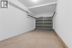 Single-car garage featuring a sectional overhead door with upper window panels, concrete flooring, white painted walls, and overhead lighting -