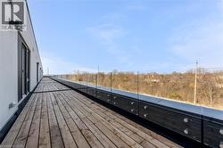 Expansive rooftop deck featuring wood-finish flooring and a contemporary glass railing system -