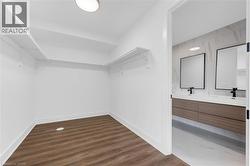 Bright walk-in closet with integrated shelving and wood-finish flooring -