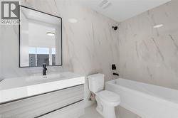 Bathroom featuring a built-in bathtub with matte black fixtures, a white toilet, and a vanity with an integrated sink -