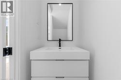 Contemporary floating vanity with integrated sink, matte black faucet, and a sleek black-framed mirror -