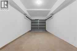 Spacious garage featuring a light gray sectional garage door, smooth concrete flooring, and white painted walls -