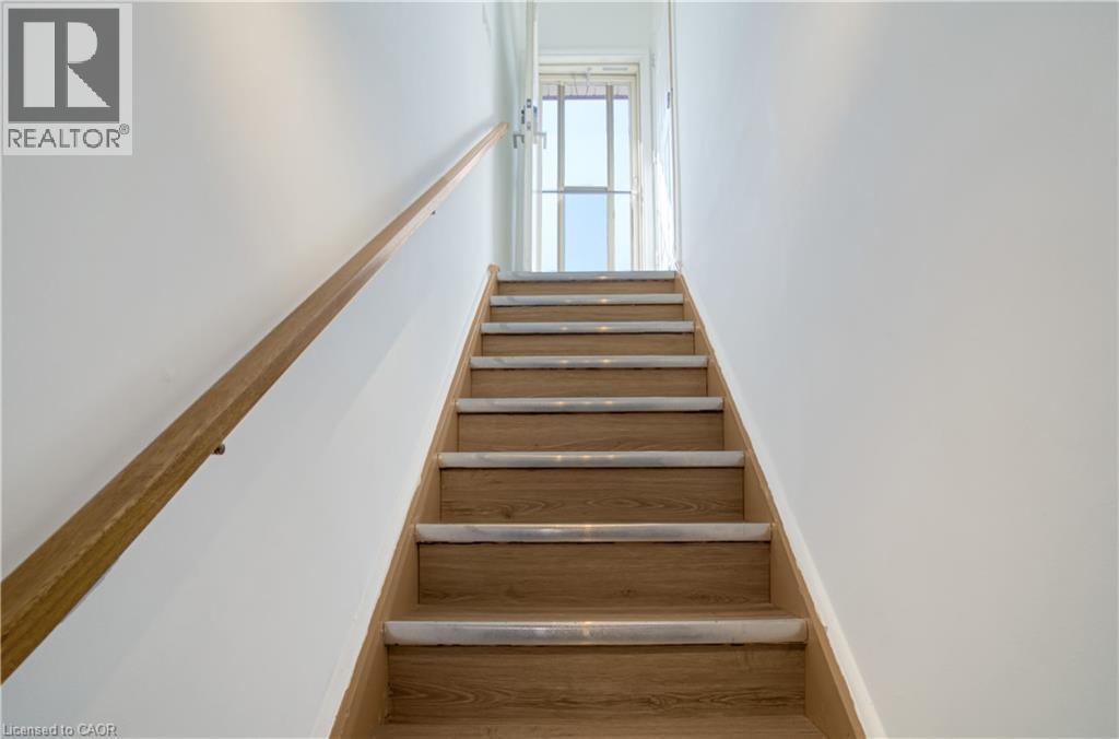Staircase featuring wood-finish treads with light-toned risers, a wood-finish handrail, white walls, and a window providing natural illumination - 60 Lysanda Avenue, London, ON - Indoor Photo Showing Other Room