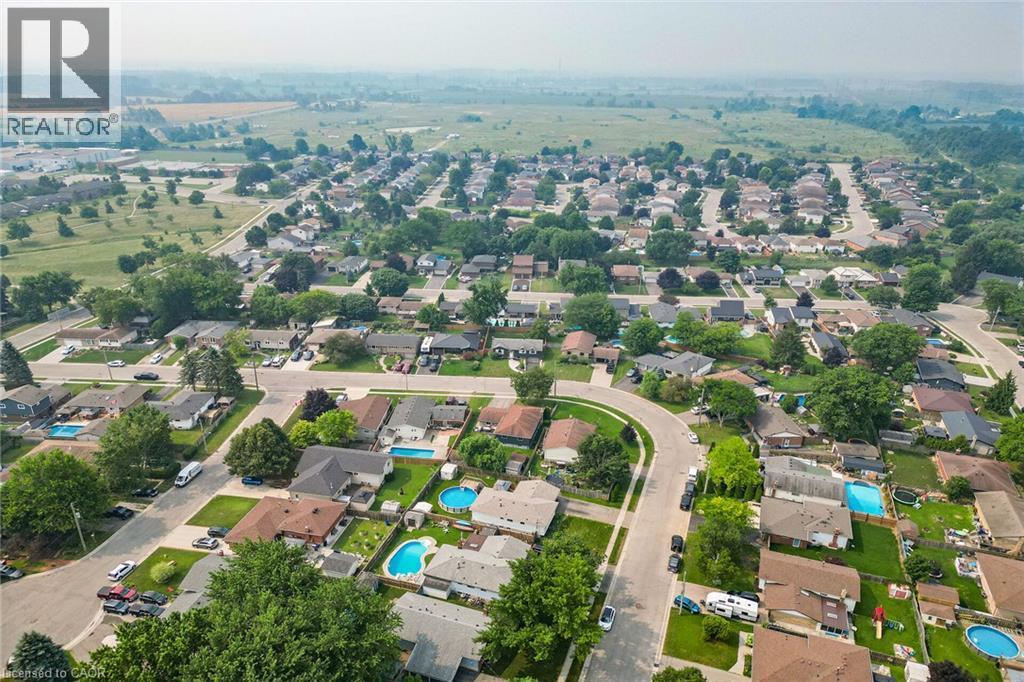 Aerial perspective of a residential neighborhood featuring detached homes on tree-lined streets, multiple properties with in-ground pools, and surrounding green spaces - 186 Glenmor Drive, Caledonia, ON - Outdoor With View