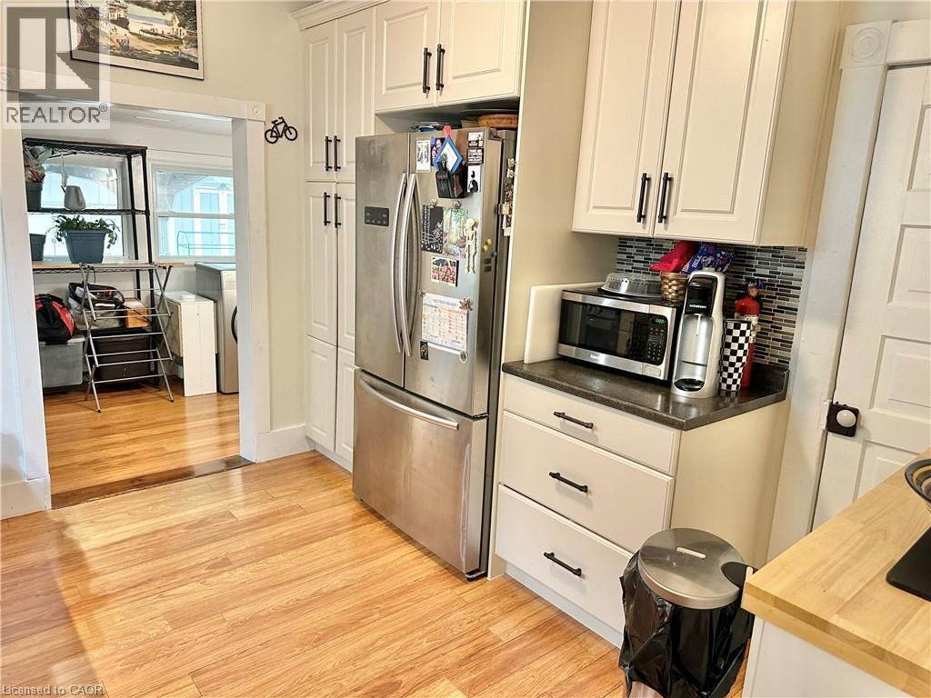 Kitchen featuring white shaker cabinetry, stainless steel refrigerator, dark countertops, and a mosaic tile backsplash - 88 Brook Street, Simcoe, ON - Indoor Photo Showing Kitchen