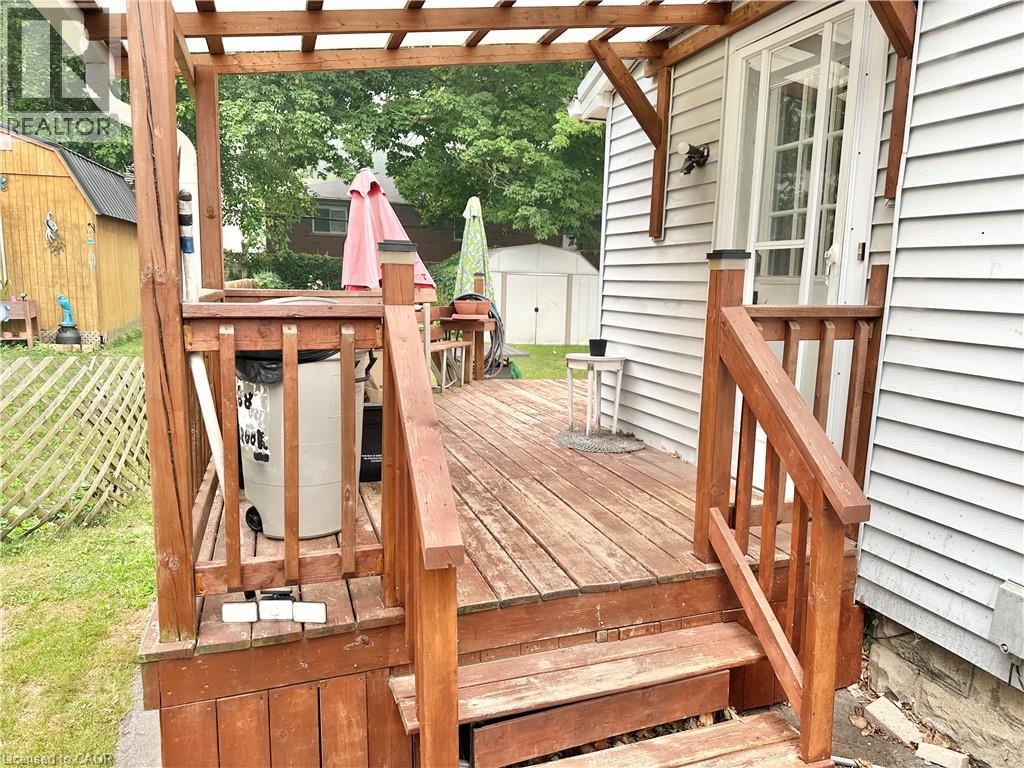Wood-finish deck with pergola framing, featuring built-in railing, steps, and a glass-paneled exterior door - 88 Brook Street, Simcoe, ON - Outdoor