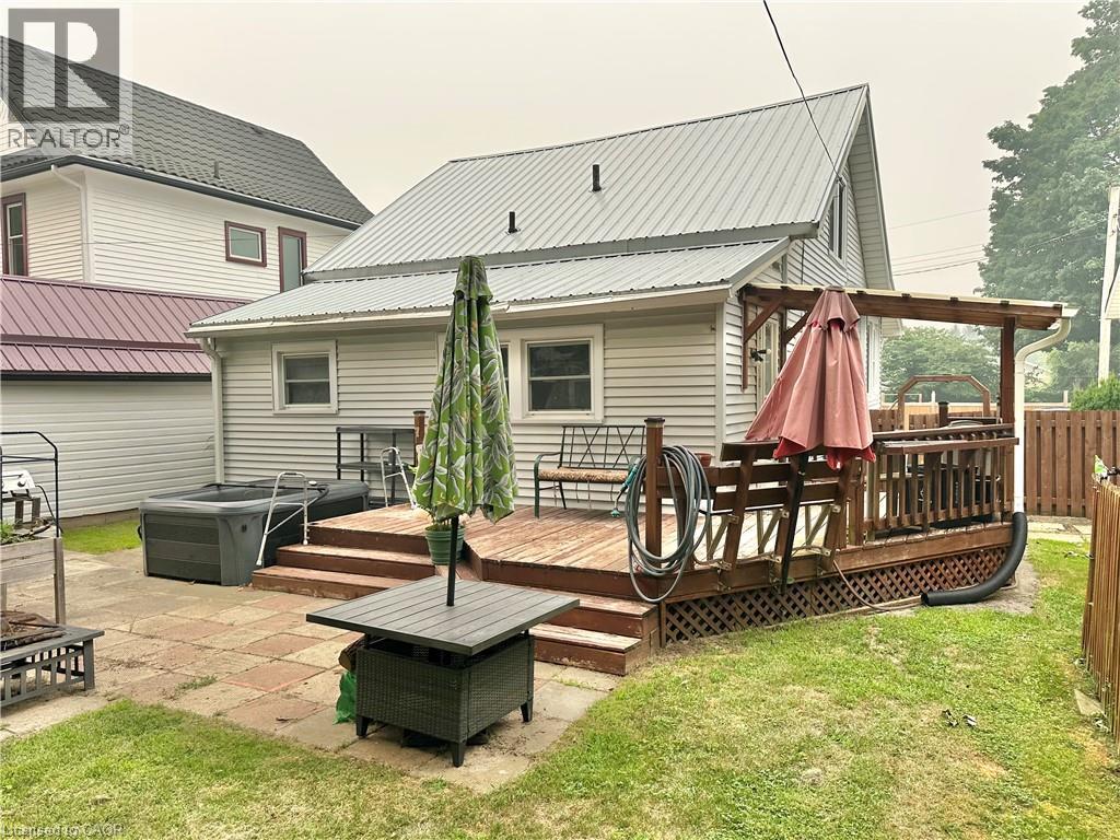 Rear exterior featuring a multi-level wood deck with pergola, metal roofing, and a stone paver patio - 88 Brook Street, Simcoe, ON - Outdoor With Deck Patio Veranda With Exterior